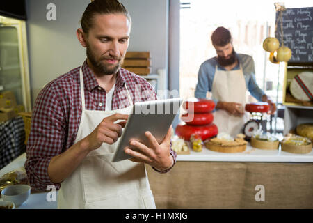 Attentive staff using digital tablet at counter in market Stock Photo