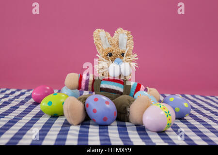 Various Easter eggs with soft toy against pink background Stock Photo