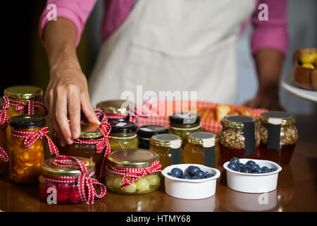 Mid-section of staff arranging jar at counter in market Stock Photo