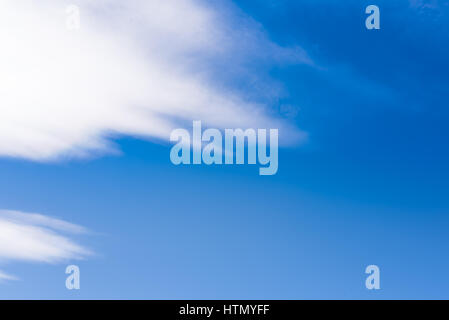 Blue saturated sky background with diagonal clouds on the left side Stock Photo