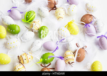 Easter eggs dotted, painted, decorated with feathers on white background. Easter decorations Stock Photo