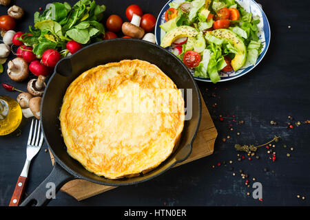 Omelette in a pan with spices, vegetables salad, radishes, mushrooms, overhead shot, healthy breakfast meal Stock Photo