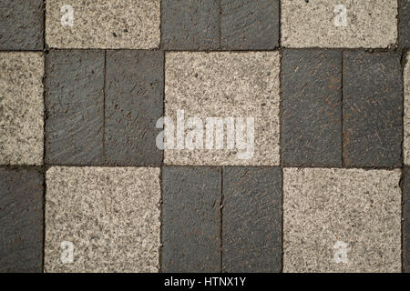 Weathered dark and light gray brick sidewalk in a checkerboard pattern. Stock Photo