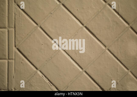 A tan painted brick wall.  The bricks are laid diagonally. Stock Photo