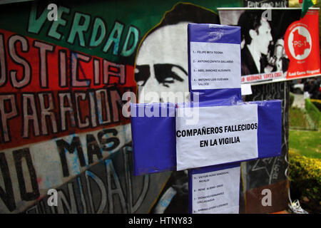 La Paz, Bolivia, 13th March 2017. A mural showing Marcelo Quiroga Santa Cruz on the wall of the camp set up by victims of Bolivia's military dictatorships opposite the Justice Ministry building. Today the victims commemorate 5 years of protests demanding justice and compensation for those that suffered, and that the government releases files from the period to help establish the truth about what happened. The cross in the foreground has the names of 22 protestors / survivors who have died since the protests started. Credit: James Brunker / Alamy Live News Stock Photo