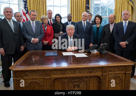 Washington DC, USA 13th March, 2017 US President Donald J Trump (C) delivers brief remarks before signing an executive order entitled, 'Comprehensive Plan for Reorganizing the Executive Branch', beside members of his Cabinet in the Oval Office of the Whit Stock Photo