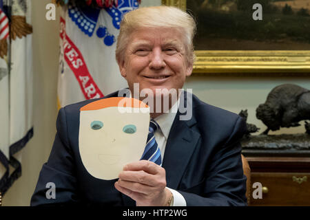 Washington DC, USA 13th March, 2017 US President Donald J Trump holds up a note and drawing depicting him that was created by the child of Greg Knox of Ohio, during a meeting on healthcare in the Roosevelt Room of the White House in Washington, DC, USA, 1 Stock Photo