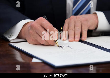 Washington DC, USA 13th March, 2017 US President Donald J Trump signs an executive order entitled, 'Comprehensive Plan for Reorganizing the Executive Branch', beside members of his Cabinet in the Oval Office of the White House in Washington, DC, USA, 13 M