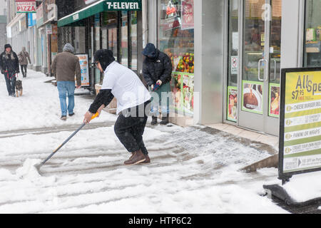 New York, USA. 14th Mar, 2017. Workers shovel snow in the Chelsea neighborhood of New York on Tuesday, March 14, 2017. Originally predicted as a blizzard with up to 20 inches of snow the storm has changed its course and only 4 to 6 inches of snow, sleet and rain are expected, accompanied by howling winds of course. ( © Richard B. Levine) Credit: Richard Levine/Alamy Live News Stock Photo