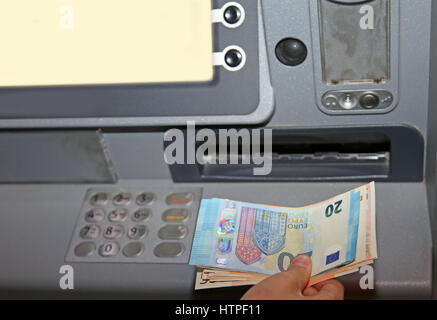 boy who withdraws money from an ATM machine in euro banknotes in europe Stock Photo