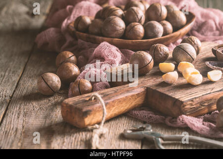Macadamia nuts on cutting board over wooden table Stock Photo