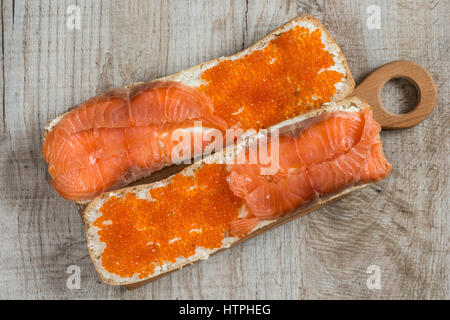 sandwiches with red caviar and salmon on wooden background Stock Photo