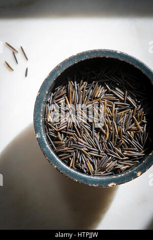 Wild rice in a ceramic black bowl on a marble backdrop Stock Photo