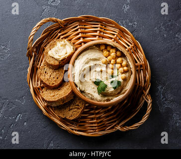 Homemade hummus and bread on wicker tray on black stone background Stock Photo