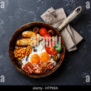 English Breakfast in cooking pan with fried eggs, sausages, bacon and beans on dark stone background Stock Photo