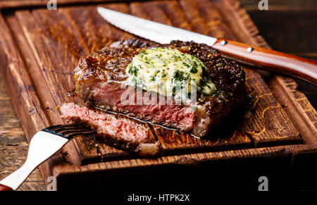 Grilled Medium rare steak Ribeye with herb butter on cutting board serving size Stock Photo