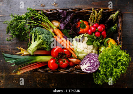 Fresh vegetables in basket on wooden background Stock Photo