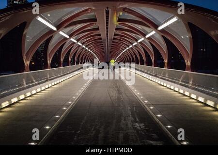 Cyclist travels across the Peace Bridge towards downtown, commuting to the urban city center Stock Photo
