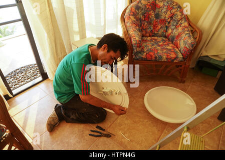 Mexican electrician fixing light fixture in Mexico. Stock Photo