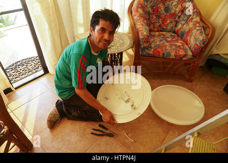 Mexican electrician fixing light fixture in Mexico. Stock Photo