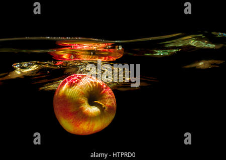 Apples in water with reflrction and splash on black background Stock Photo