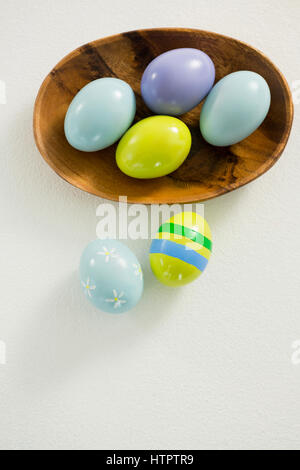 Colorful Easter eggs in bowl with two painted Easter eggs on white background Stock Photo