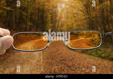 seeing forest path in autumn through glasses that improve vision Stock Photo