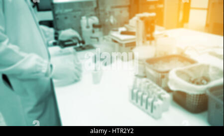Out of focus young researcher works in chemistry laboratory as background. Stock Photo