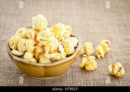 Fresh popcorn in bowl on sack background. Stock Photo