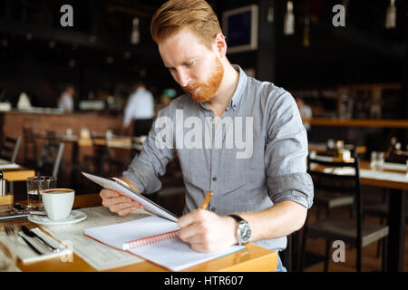 Businessman taking notes in cafe and writing down ideas Stock Photo