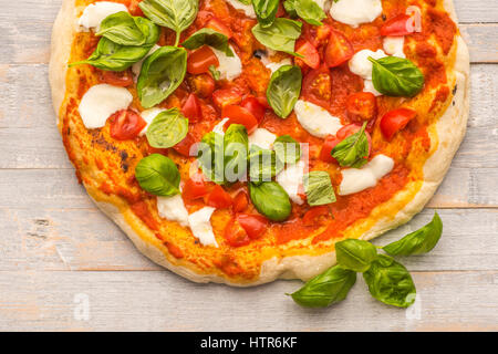Feshly made wood fired pizza viewed from above on rustic grey boards Stock Photo