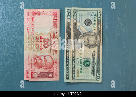 Close-up of Indian 20 Rupee Note and American 20 Dollar bill on plain background Stock Photo