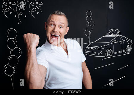 I am the winner. Overjoyed delighted adult man expressing jubilation while feeling happy because of winning a car Stock Photo