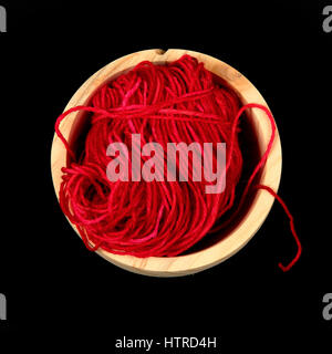 One ball of red wool in a wooden bowl from above Stock Photo