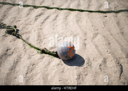 A float tied to a rope laying on golden sand during low tide in the harbour at St Ives, Cornwall, England, UK. Stock Photo