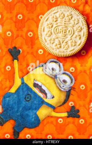 Golden Oreo biscuits on serviette with Minions - Minion juggling with Golden Oreo biscuit, sandwich biscuits with a vanilla flavour filling Stock Photo