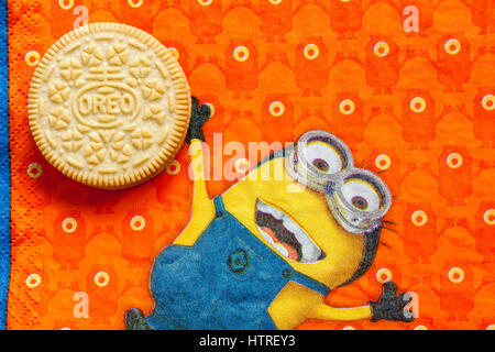 Golden Oreo biscuits on serviette with Minions - Minion juggling with Golden Oreo biscuit, sandwich biscuits with a vanilla flavour filling Stock Photo
