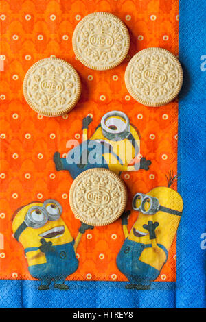 Golden Oreo biscuits on serviette with Minions - Minions juggling with Golden Oreo biscuits, sandwich biscuits with a vanilla flavour filling Stock Photo