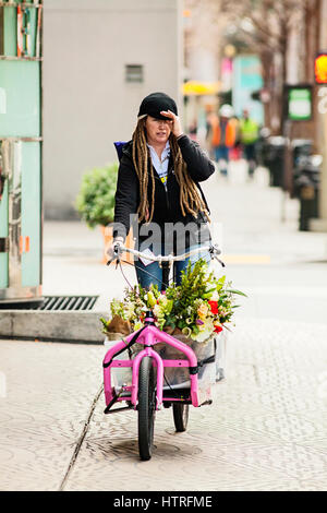 Woman delivering flowers from a bicycle. Stock Photo