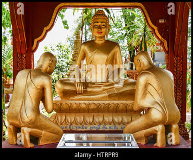 Golden statues of Buddha and two monks at a temple in Cambodia. Southeast Asia Stock Photo