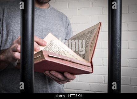 A prisoner reading in his cell in prison. Photo posed by model to illustrate education and reform in prison Stock Photo