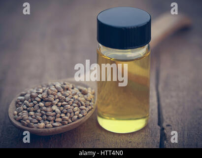 Seeds of Cannabis or hemp with essential oil in bottle on timber surface Stock Photo
