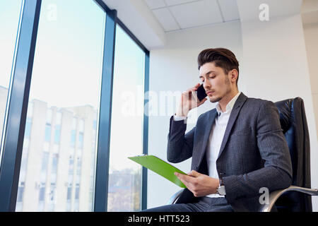Businessman with documents hands of talking on a cell in modern office. Stock Photo