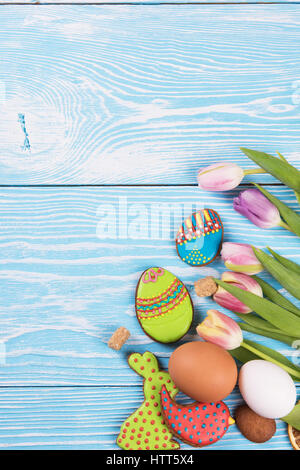 Tulips and gingerbread cookies on white and blue wooden background for Easter. Stock Photo