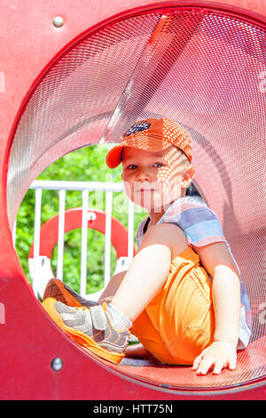 Cute kid boy playing in tunnel on playground Stock Photo