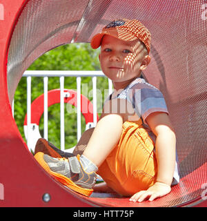 Cute kid boy playing in tunnel on playground Stock Photo