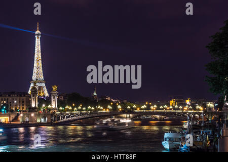 The Eiffel Tower at night all lit up in Paris, France, with Pont Alexandre III bridge in foreground Stock Photo