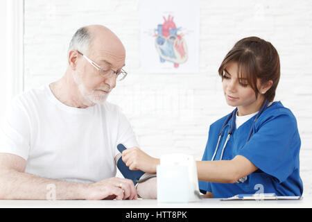 Doctor measuring blood pressure of male senior patient Stock Photo