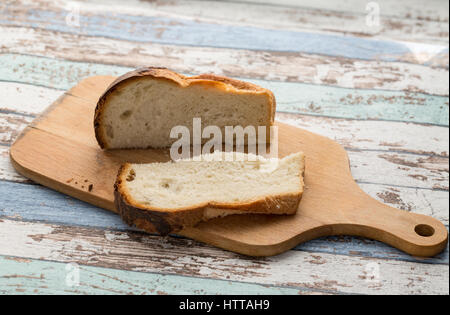 slice and bread loaf on cutting board on turquoise vintage table Stock Photo