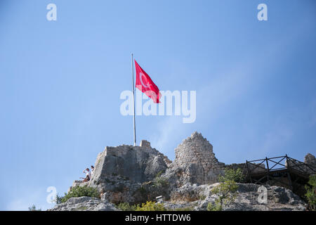 Ancient ruins and flag of Turkey over simena castle in Uchagiz bay shot on sunny day with blue sky Stock Photo